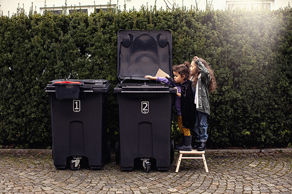 Barn som sorterar avfall i ett kärl